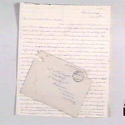 Single paged letter with handwritten text, stamped envelope laying on top of letter.