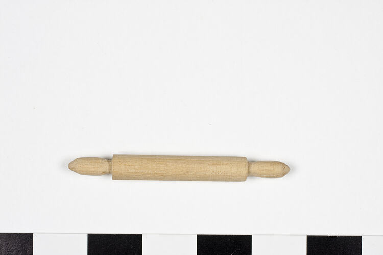 Small wooden rolling pin with turned ends.