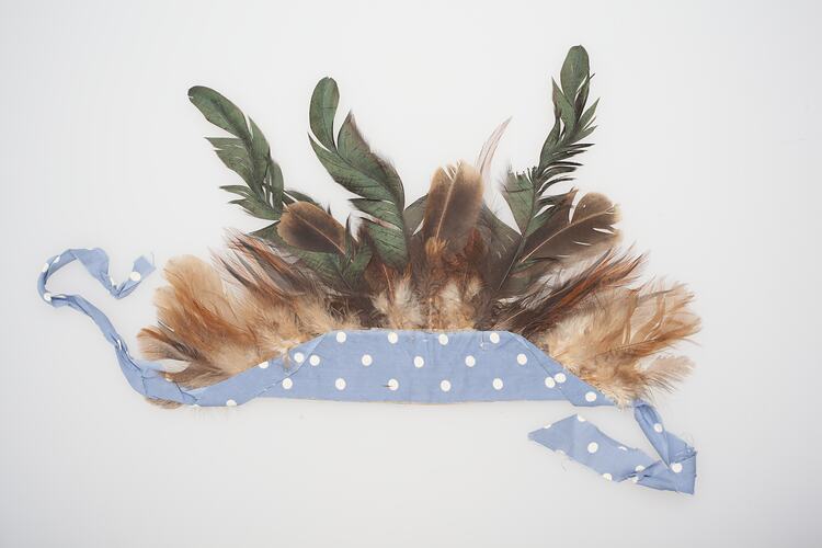 Feathered headdress. Brown and green feathers mounted in a blue and white spotted band.