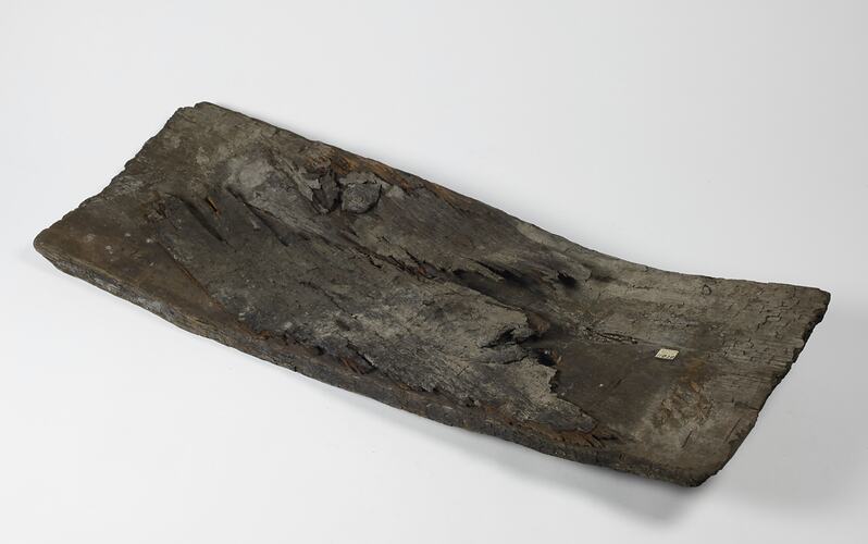 Rectangular warped piece of wooden ship plank.