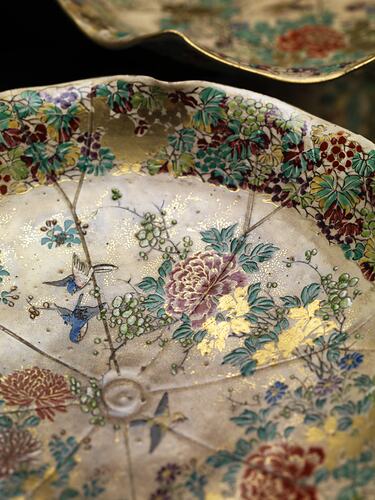 Detail of cream coloured compote with wavy edges decorated with birds & chrysanthemums.