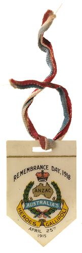 Plastic badge with coat of arms and printed text and red, white and blue textile ribbon.