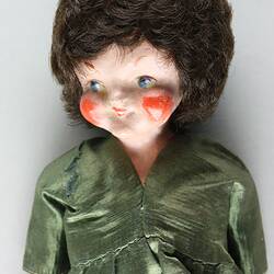 Female doll, porcelain head with short brown hair. Soft body. Wearing olive green satin dress. Detail of head and body.