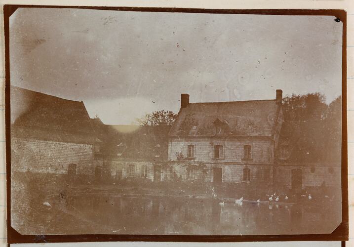 Two storey farm house with a lake in front.