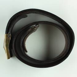 Leather belt with buckle, belt rolled into circle, top view.