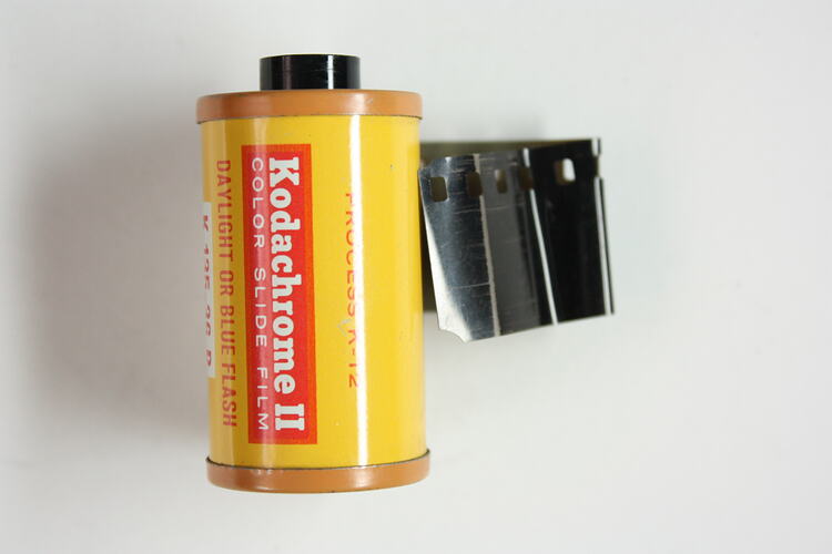 Cylindrical cartridge with 35mm film protruding from side.