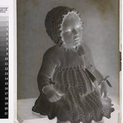 Negative, female toddler in knitter dress and bonnet.