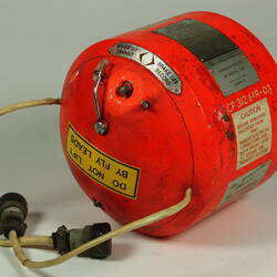 Red cylindrical container with two electrical cords at one end.