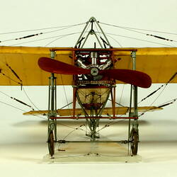 Model aeroplane with exposed wooden frame and off white panelling. Front view.