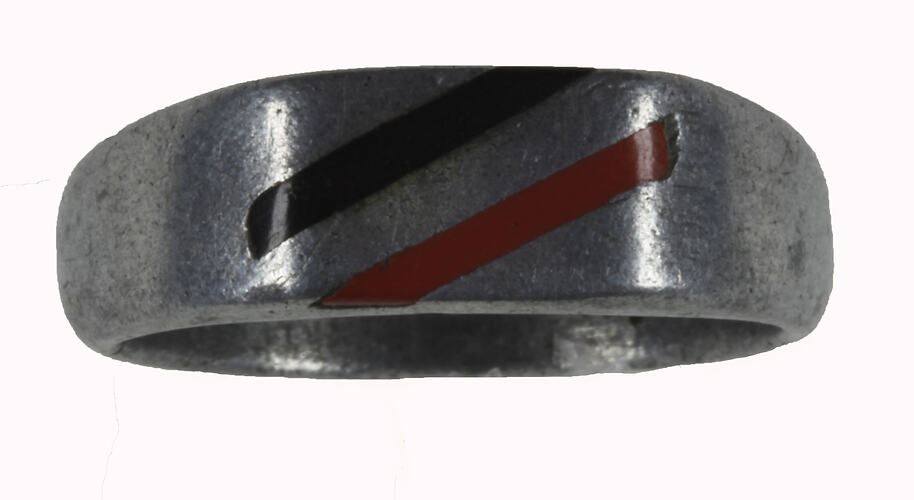 Darkened worn aluminium metal ring with two inlaid diagonal strips in black and brown.