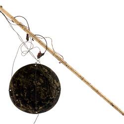 Bone stick with measurement marks attached to brass disc via string.