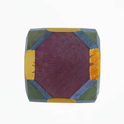 Wooden crystal model painted mauve, yellow, green and blue.