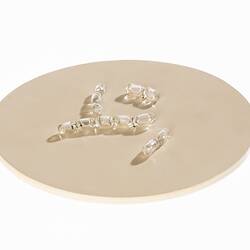 Light brown disc with clear glass capsule-shaped pieces on top.