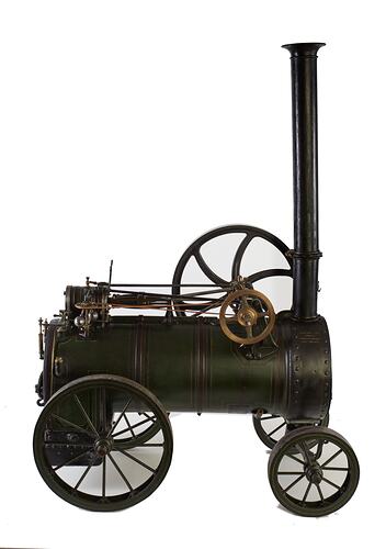 Model of black moveable steam engine on four wheels with tall chimney at front. Right profile.