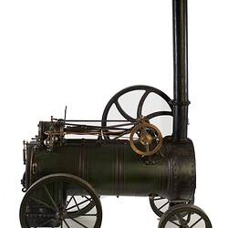 Model of black moveable steam engine on four wheels with tall chimney at front. Right profile.