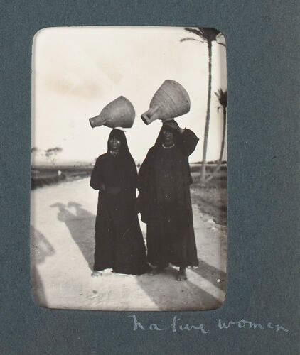 Two women carrying pots on their heads.