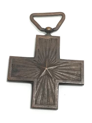 Dark metal cross medal with raised star at centre. Loop at top.