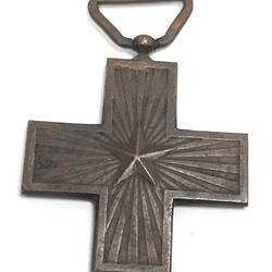 Dark metal cross medal with raised star at centre. Loop at top.