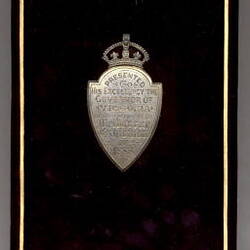 Black rectangular box with engraved silver shield at  centre.