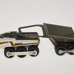 Cream six-wheeled toy truck with grey two-wheeled trailer. Stickers on sides. Left profile.