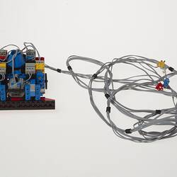 Grey cables attached to black, blue, red, yellow and grey plastic component.