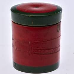 Red painted, cylindrical wooden box. Dark green trim around lid and base.