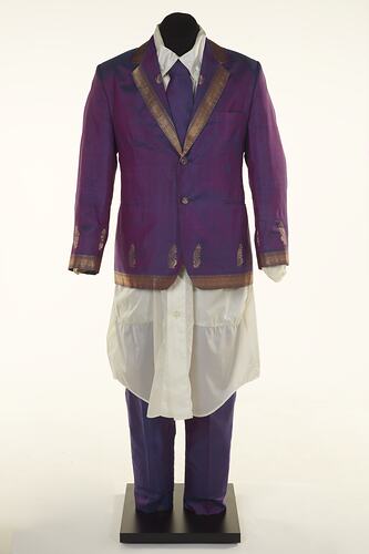 Purple sari two-piece suit and matching tie, long off-white shirt. Gold detail on jacket edging.