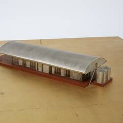 Model of a house with an arched roof, corrugated iron and wide expanses of glass.