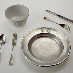 Metal plate with cutlery and bowl.