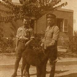 Two men in partial Light Horse uniform, posing with a young donkey.