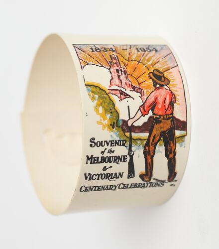 White serviette ring. Pioneer with gun looking at the city of Melbourne. Text below.