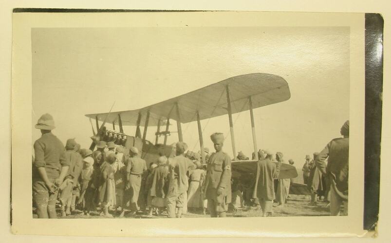 Crowd of people gathered around an aeroplane, some in military uniform.