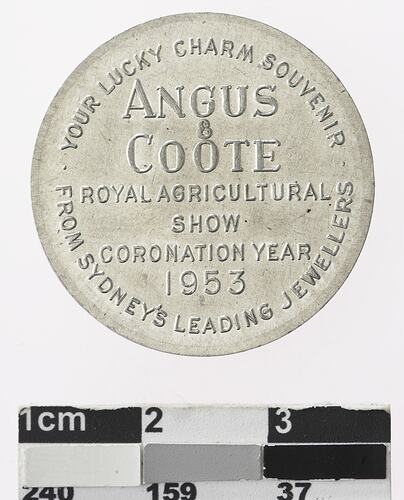 Round silver coloured medal with text.