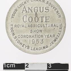 Round silver coloured medal with text.