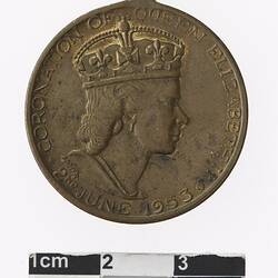Round bronze coloured medal with profile of crowned woman and text surrounding.