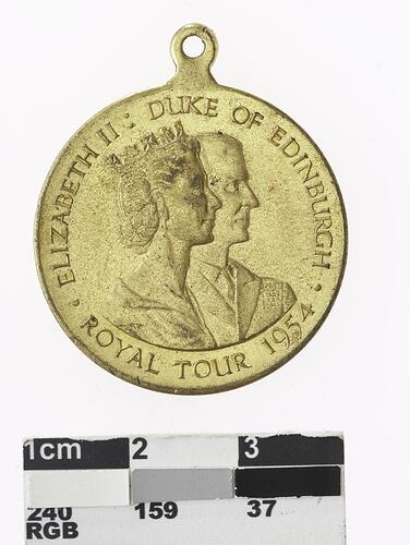 Round gold coloured medal with profile of man and crowned woman, text surrounding.
