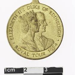 Round gold coloured medal with profile of man and crowned woman, text surrounding.