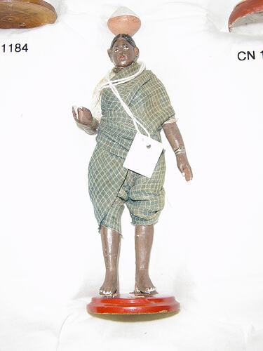 Clay figurine of washer woman wearing blue and white checquered cotton sari.