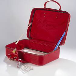 Open, red vinyl suitcase.