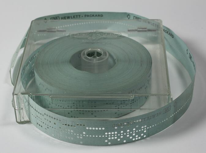 Clear hinged plastic box with holed paper tape inside.
