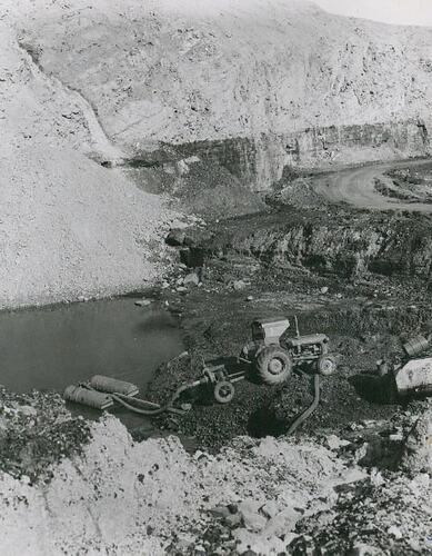 A tractor coupled to a PTO driven pump in the base of a quarry.