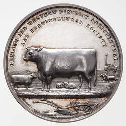Round silver medal with cattle, sheep, harnessed horses, portable engine in background. Text along top edge.
