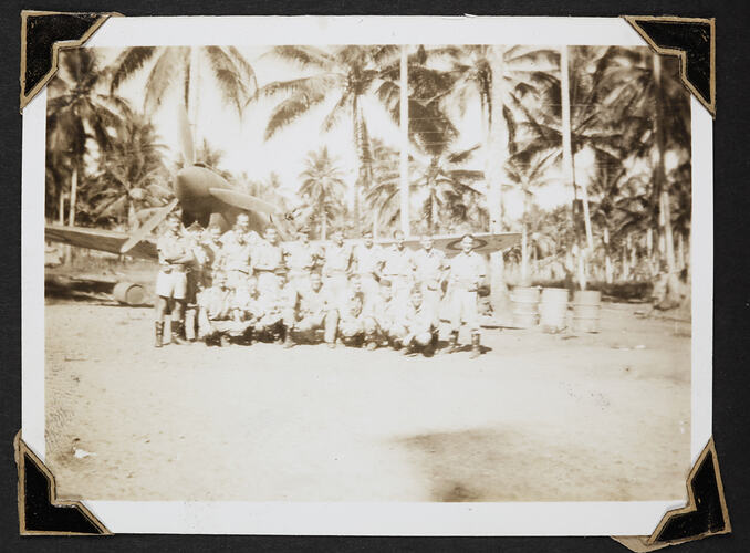 Group portrait of men in military uniform with plane behind.