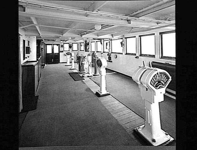 Ship interior. Wheel house. Free-standing equipment in centre and windows at right.