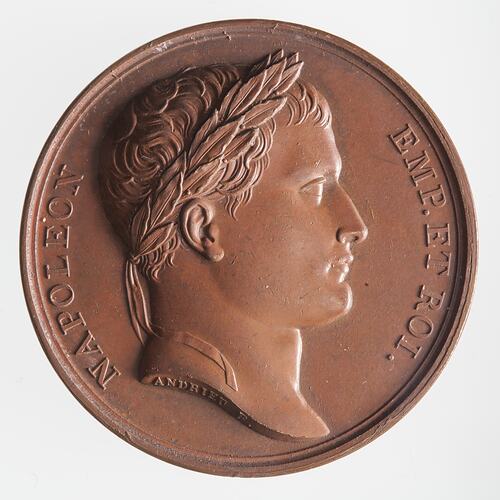 Round bronze medal with male facing right. Text around.