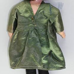 Back of female doll, porcelain head with short brown hair. Soft body. Wearing olive green satin dress.