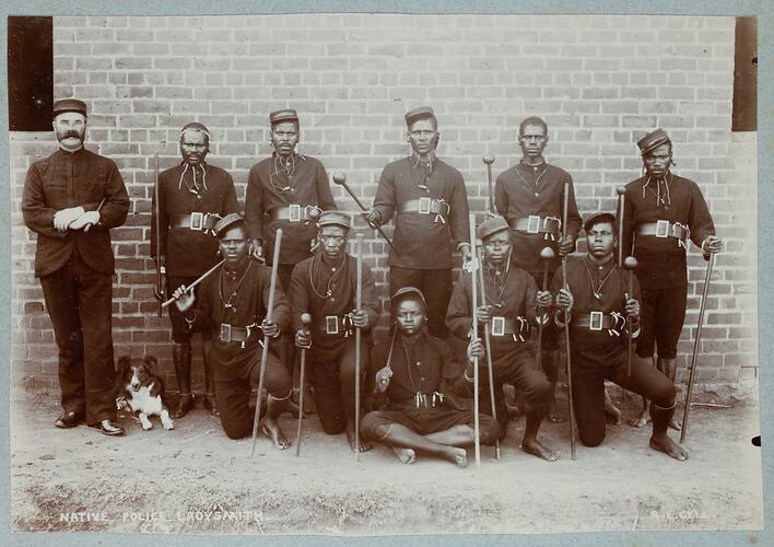 Group portrait of men in uniform holding canes.