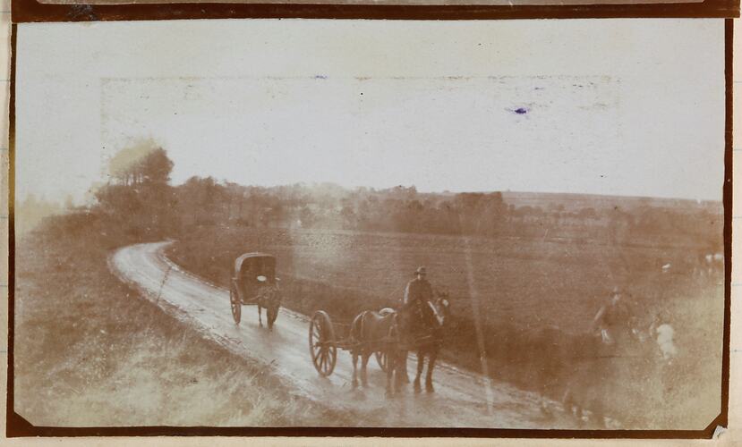 Two horse-drawn carts on a rural road.