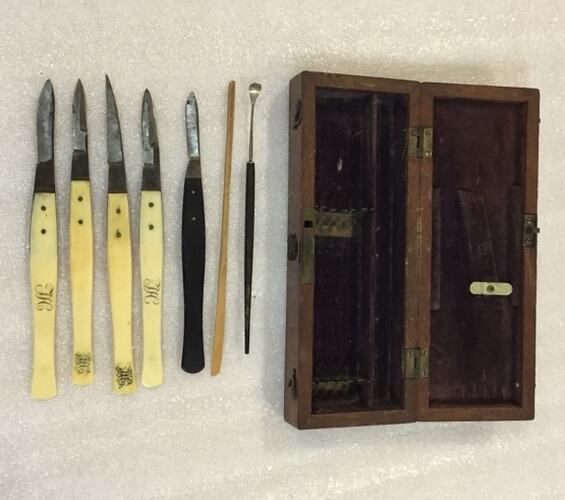 Open wooden box and seven medical instruments some with bone handles.