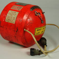 Red cylindrical container with two electrical cords at one end.